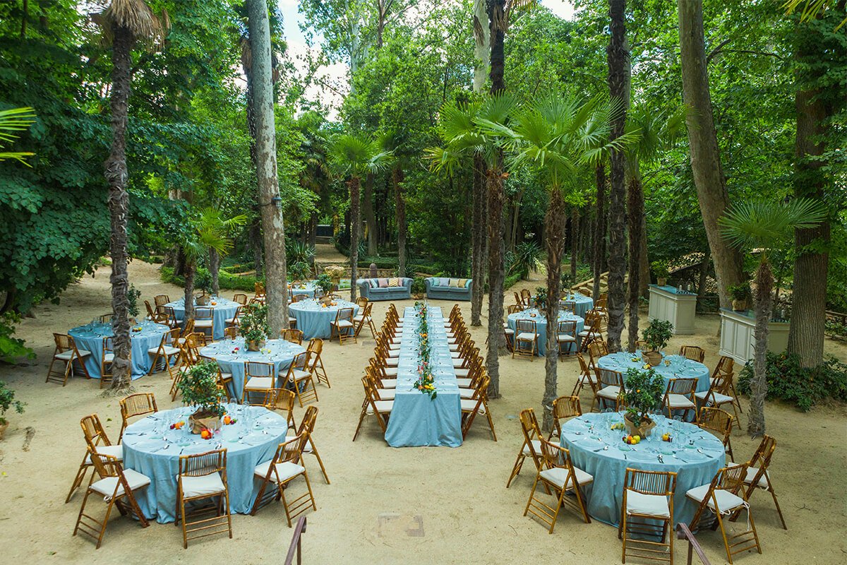 Mesas preparadas para un banquete entre árboles y palmeras